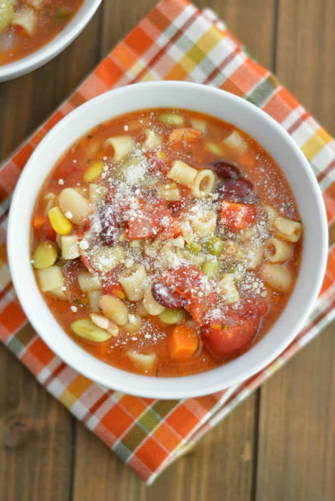 Minestrone Soup topped with Parmesan cheese on a wood table.