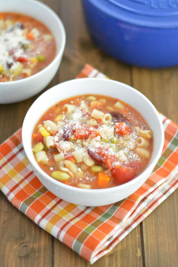 Minestrone Soup soup in a white bowl sitting on a wood table.