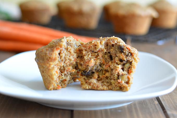 A carrot muffin cut in half sitting on a white plate.