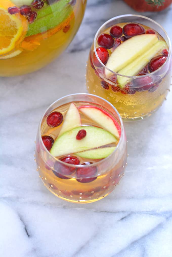 A glass of apple cider sangria topped with apples.