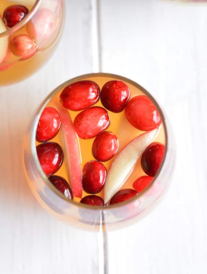 White sangria with apple slices and cranberries.