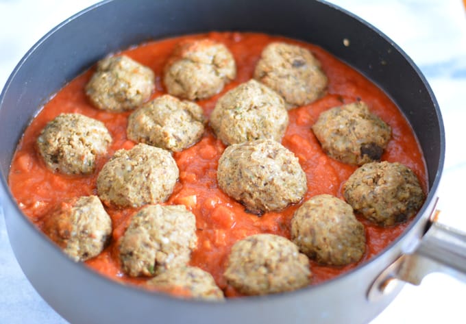 Vegetable balls made with eggplant in a pan with tomato sauce.