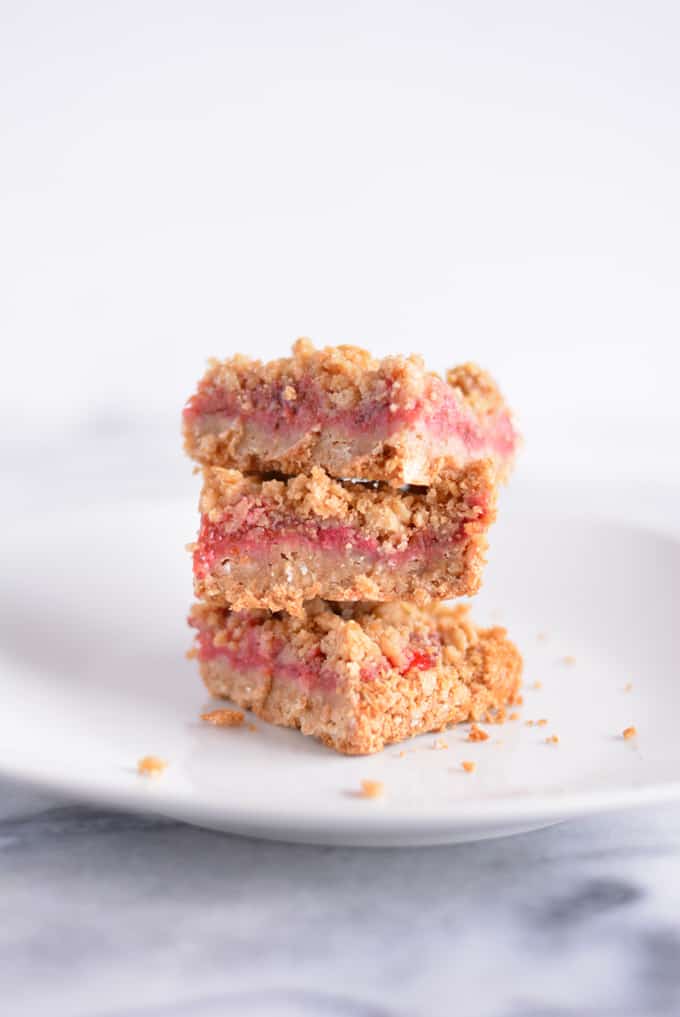 Strawberry Rhubarb Oat Crisp Bars cut and stacked on a white plate.