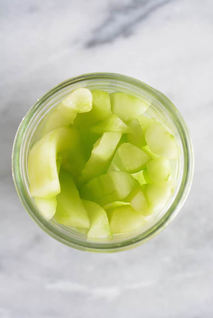 Cucumber slices inside of a mason jar.