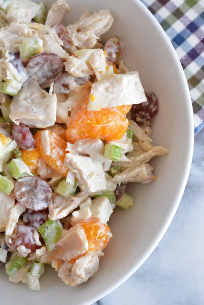 Summertime chicken salad with grapes and oranges in a white serving bowl.