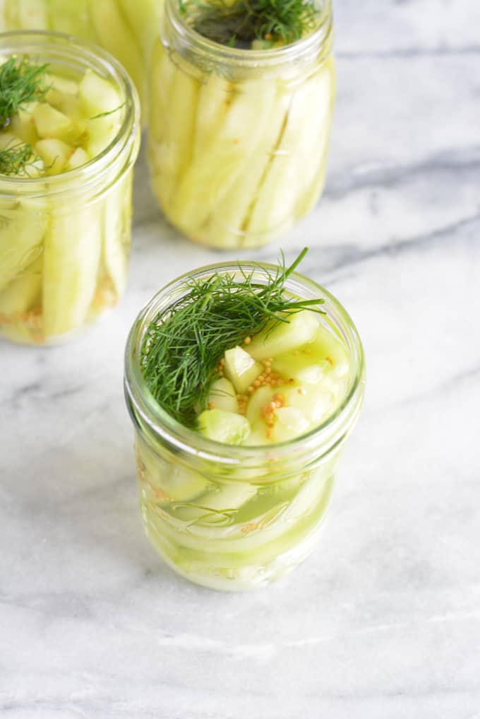 German Pickles in a mason jar on a white table.