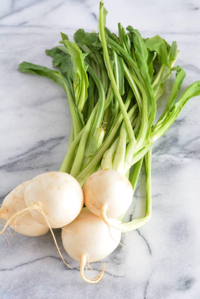 Fresh bunch of Hakurei Turnips on a white marble table.