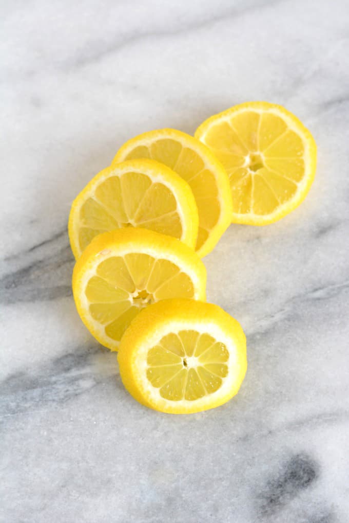 5 slices of fresh lemon on white marble table.