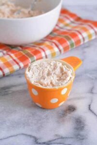 Pureed Chicken Salad in an orange and white measuring cup.