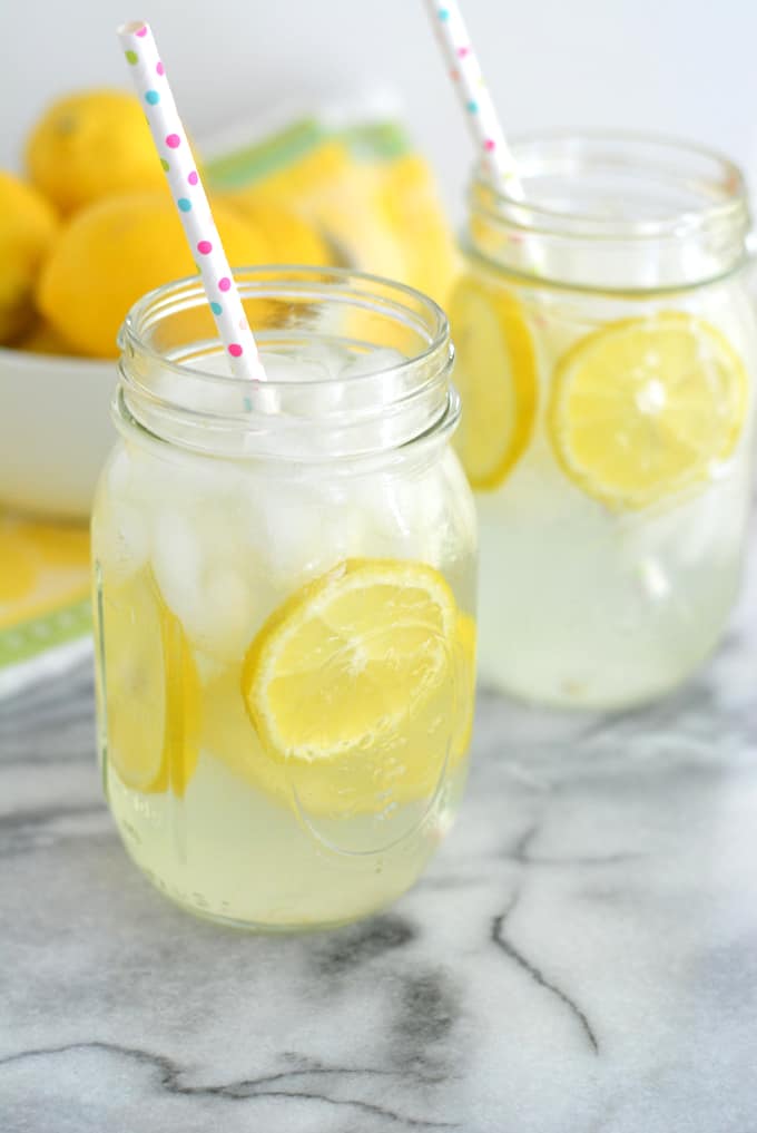 Homemade Lemonade with sliced lemons in a mason jar with a paper straw.