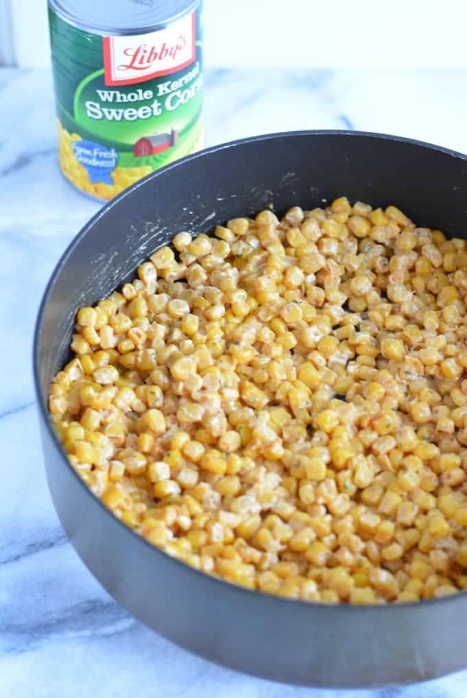 Corn cooking a saute pan next to a can of sweet corn.