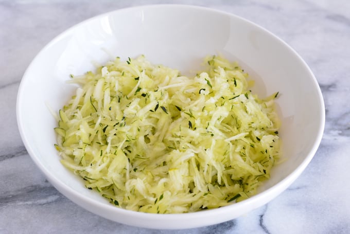 Shredded zucchini in a white bowl.