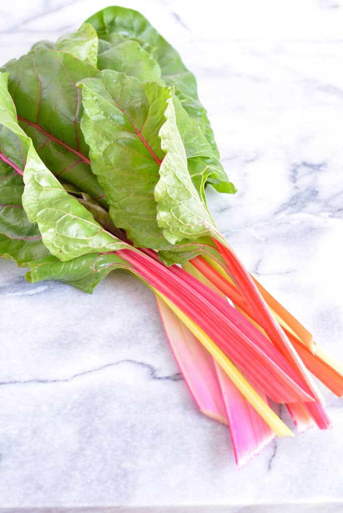 A bunch of Swiss chard on top of a white marble table.