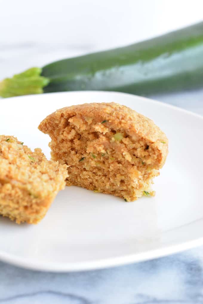 An oat bran zucchini muffin cut in half on a white plate.