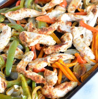 Chicken fajita mixture on top of a baking sheet.