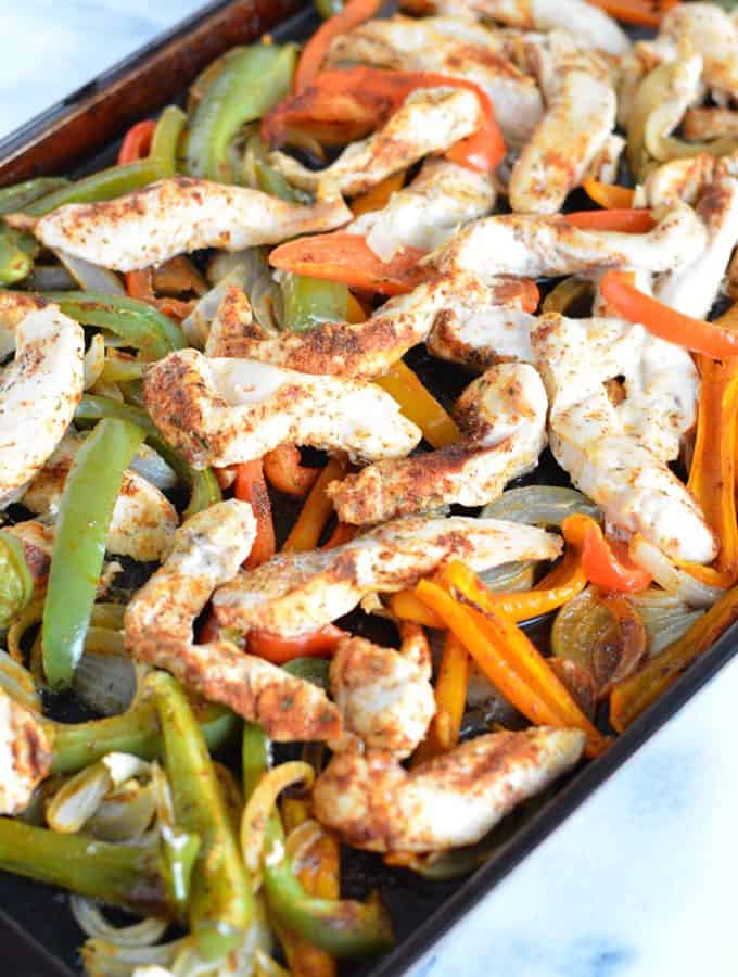 Chicken fajita mixture on top of a baking sheet.