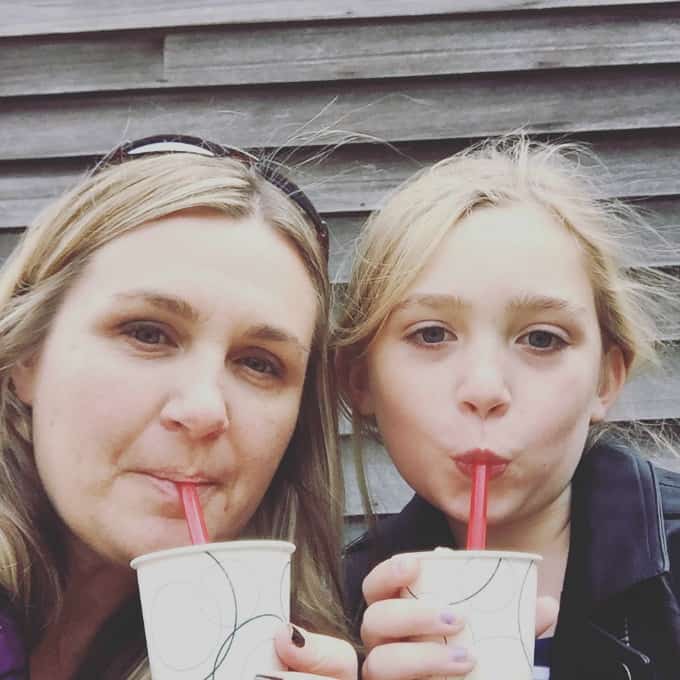 A mother and daughter drink from paper cups with red straws.