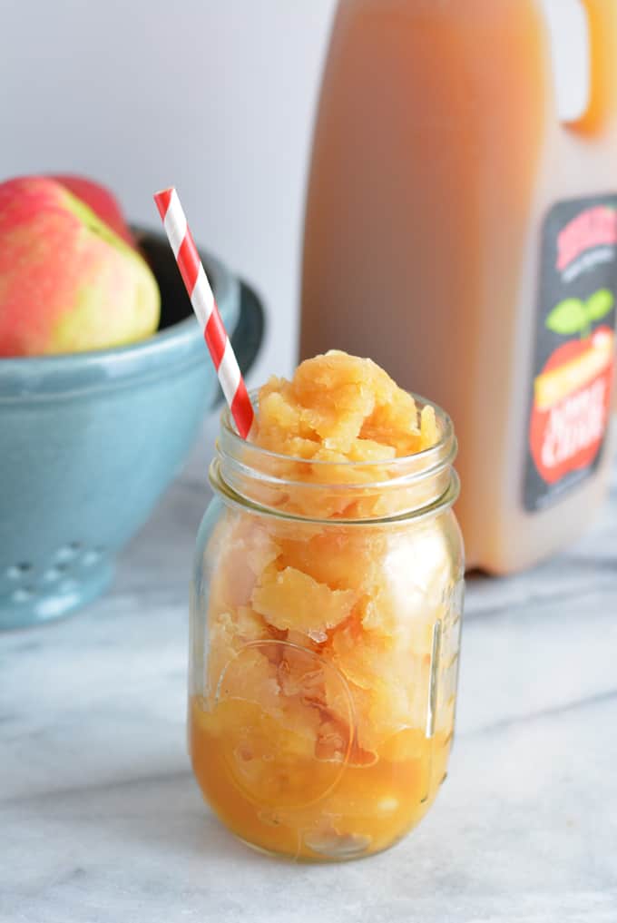 Frozen Apple Cider Slushies in a mason jar with a red and white striped straw.