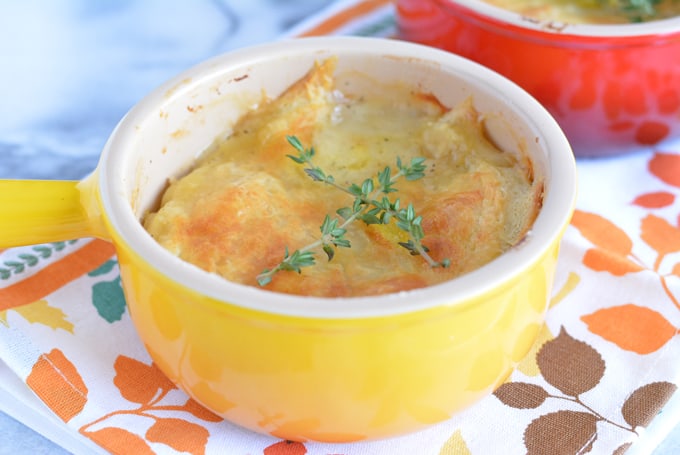 Turkey pot pie in a yellow bowl topped with a crust and two thyme spigs.