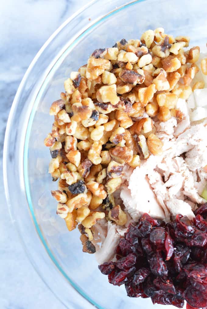 A glass bowl with walnuts, turkey and dried cranberries.