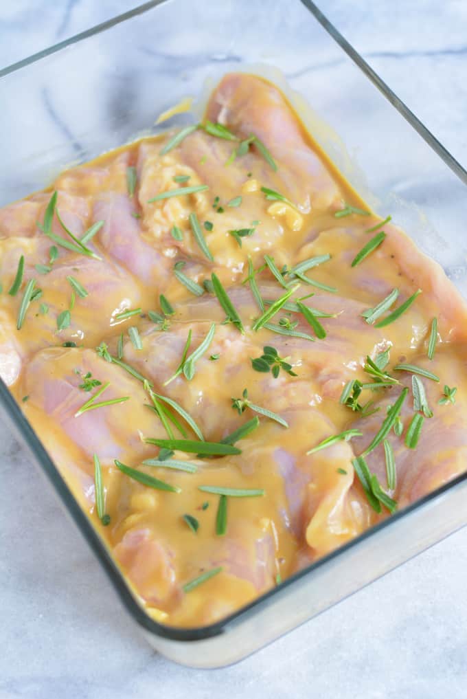 Chicken thighs marinating in a glass container