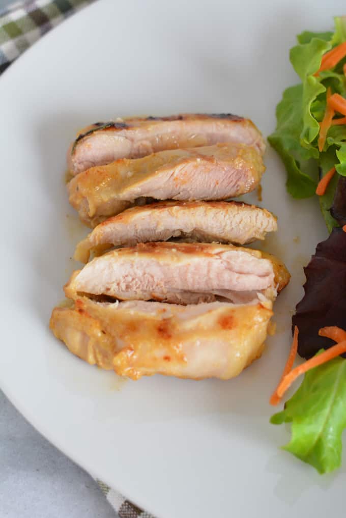 Grilled Maple Dijon chicken thighs slices on a white plate.