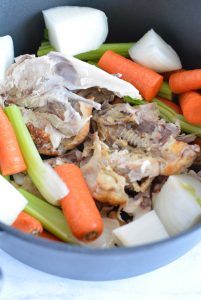 Chicken bones and vegetables in a pot.
