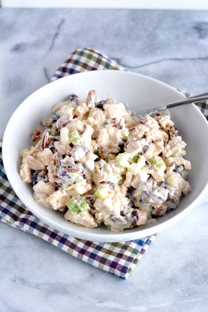 Cranberry and Pecan Chicken Salad in a white bowl with a serving spoon.