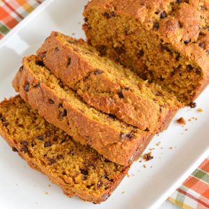Pumpkin bread with chocolate chips sliced on a white plate.